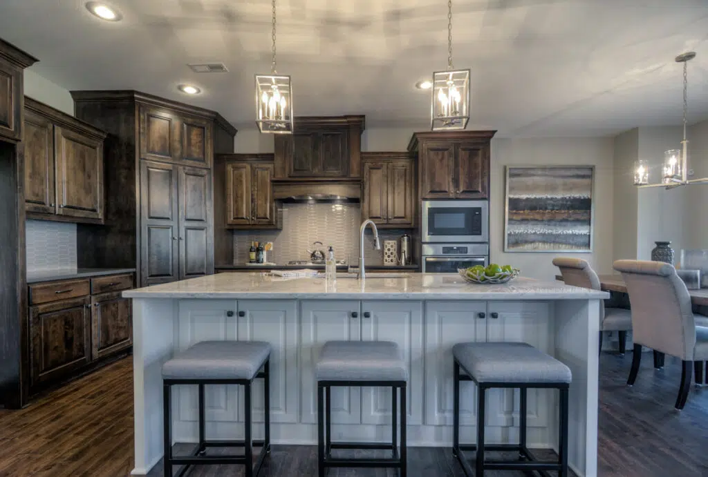 Madalena Floor Plan Kitchen With Large Island, Two-tone Cabinetry, Pendant Lighting, And Adjacent Dining Area By Comerio Homes