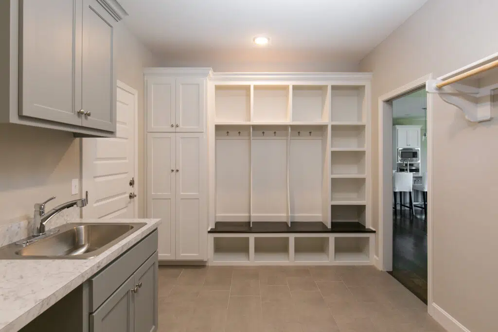 Madalena Floor Plan Mudroom With Built-in Storage, Bench, Utility Sink, And Cabinetry By Comerio Homes