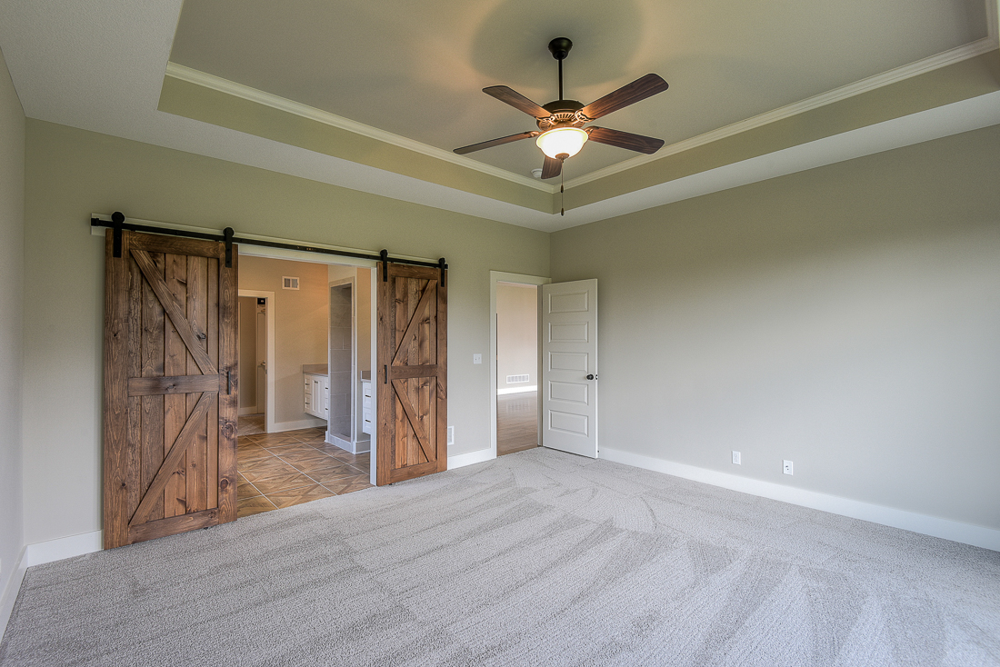 Double Rustic Wood Barn Doors Opening To The Primary Bathroom In The Varese By Comerio Homes.