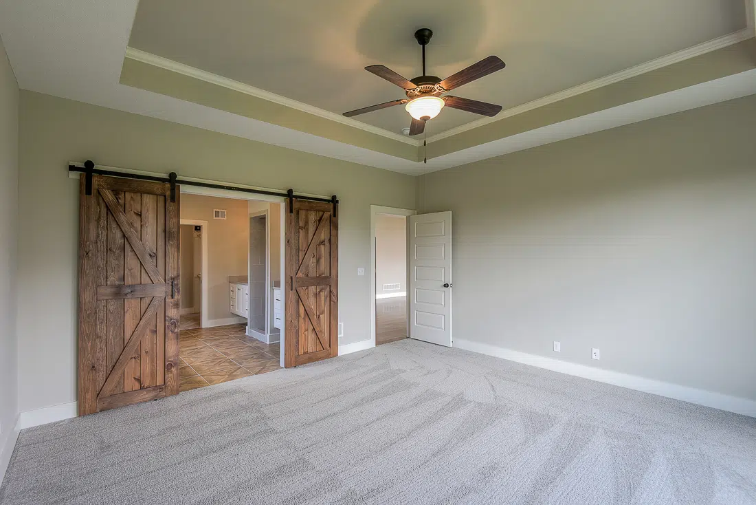 Double Rustic Wood Barn Doors Opening To The Primary Bathroom In The Varese By Comerio Homes.