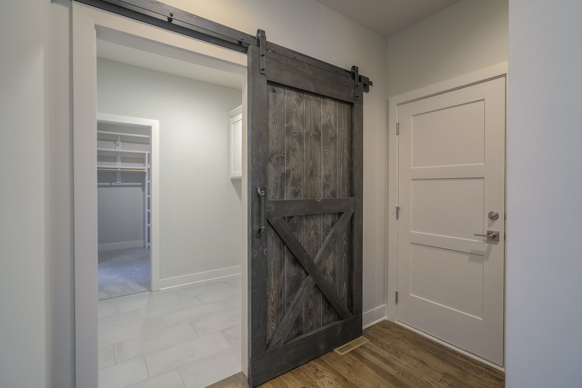 Dark Wood Sliding Barn Door At The Laundry Room In The Verona II By Comerio Homes.