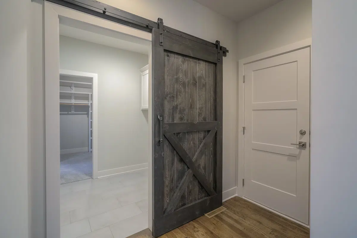 Dark Wood Sliding Barn Door At The Laundry Room In The Verona II By Comerio Homes.