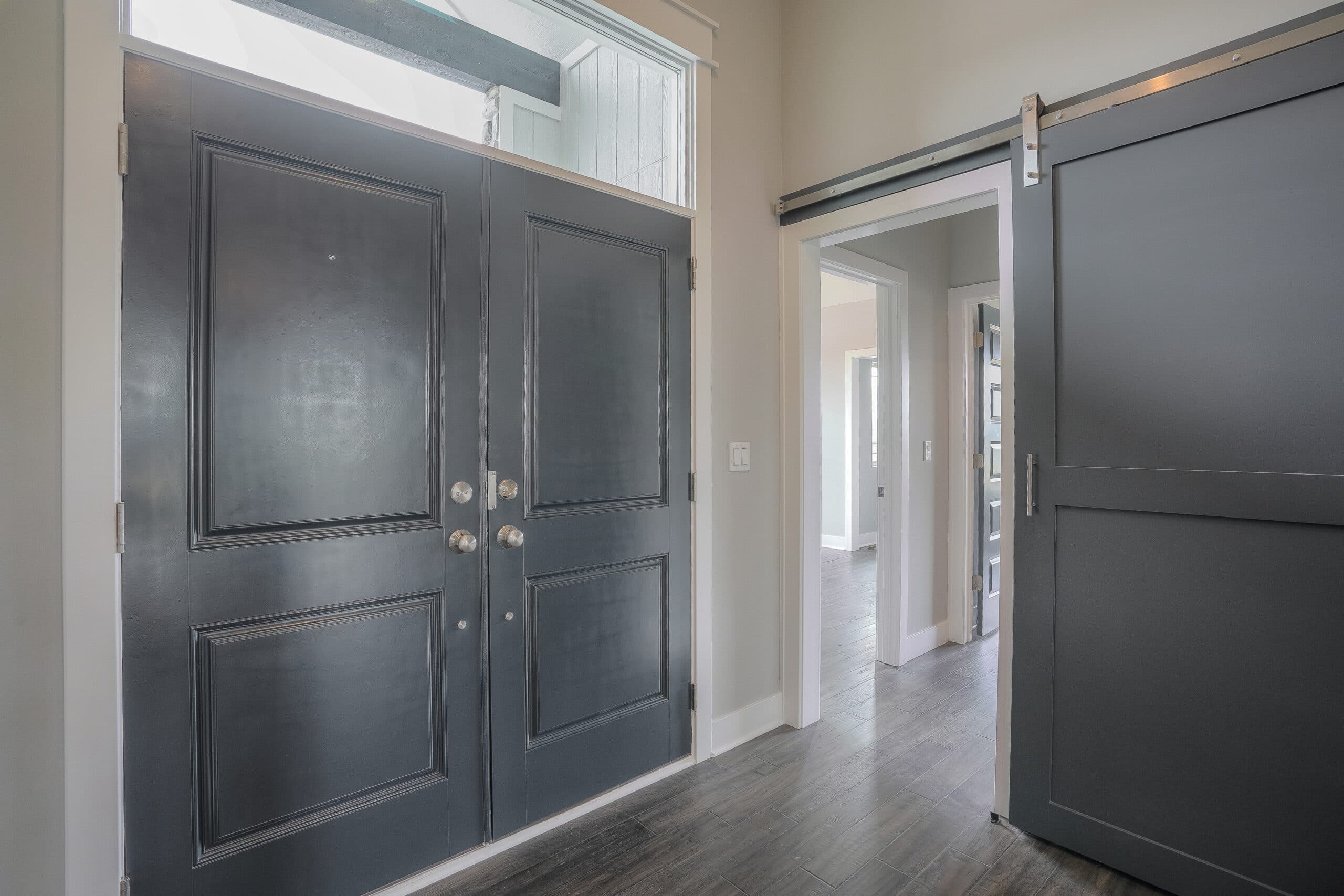 Verona III Entry By Comerio Homes Featuring Double Front Doors, A Transom Window And Sliding Barn Door.