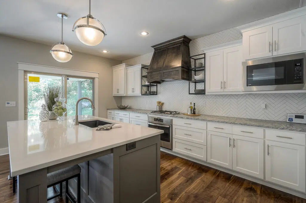 Custom Kitchen With Large Island, White Cabinetry, Pendant Lighting, And Hardwood Floors By Comerio Home