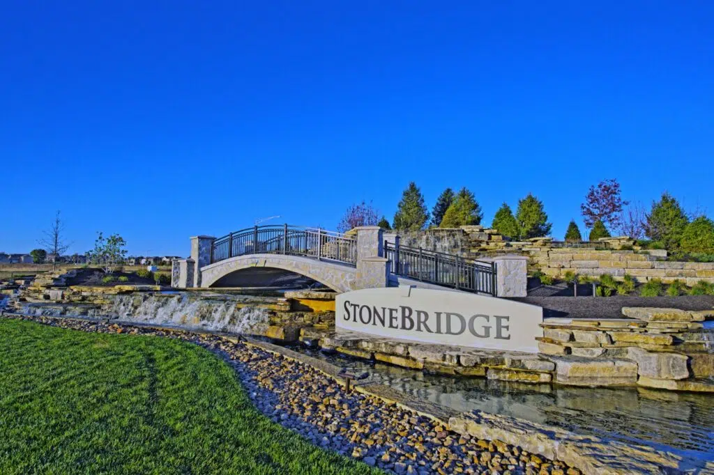 Stonebridge Community Entrance Featuring A Stone Bridge, Landscaped Water Feature, And Neighborhood Sign