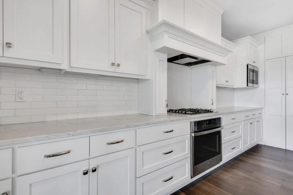 Lago Kitchen With White Cabinetry, Cooktop, And Tiled Backsplash