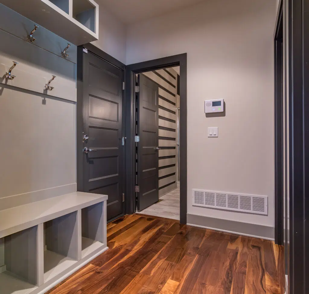 Justina Floor Plan Mudroom By Comerio Homes With Built-in Bench, Storage Cubbies, Coat Hooks And Dark Interior Doors.