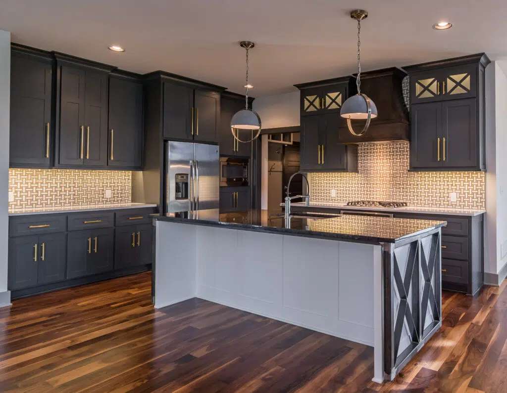 Justina Floor Plan Kitchen By Comerio Homes With Large Island, Dark Cabinetry, Brass Hardware, Custom Range Hood And Pendant Lights.
