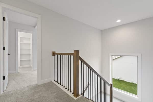 The Milano home plan's main stairwell from the upper level, showcasing a large window with ample natural light.