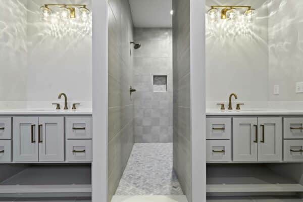 The master bathroom suite within the Varese Expanded home design by Comerio homes. The bathroom features modern, dual sinks, with access to a secluded shower/sauna area in between.