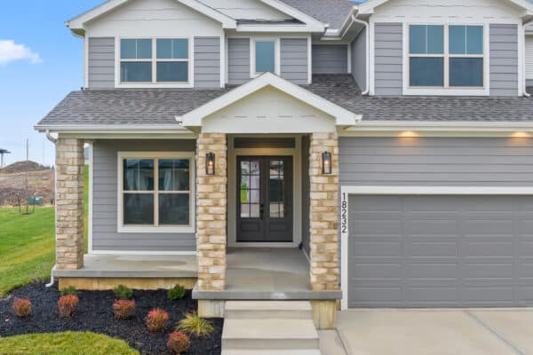 The Milano home, designed by Comerio Homes, located in Coventry Valley, Overland Park. The facade features modern siding with contrasting stone porch supports.
