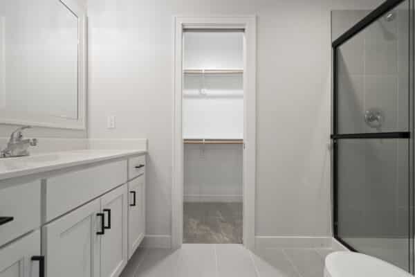 The Milano floor plan by Comerio Homes, showcasing a bathroom suite with bright finishings and polished nickel fixtures.