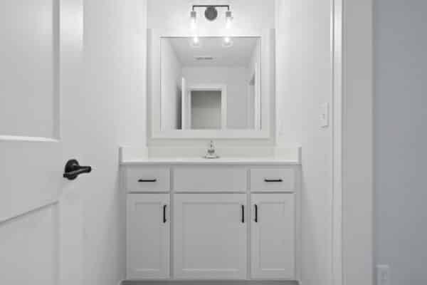A view of one of the Milano floor plan bathrooms, featuring bright cabinetry, and modern dark-finish fixtures.