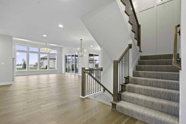 The interior of the Milano floor plan by Comerio Homes, located in Coventry Hills, Overland Park, showcasing the main level stairwell and living space.