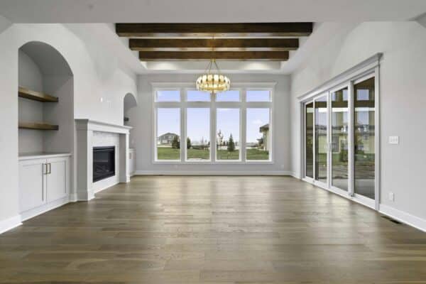 The interior of the Milano floor plan by Comerio Homes, showcasing the main living space with covered patio access and panoramic windows overlooking the yard.