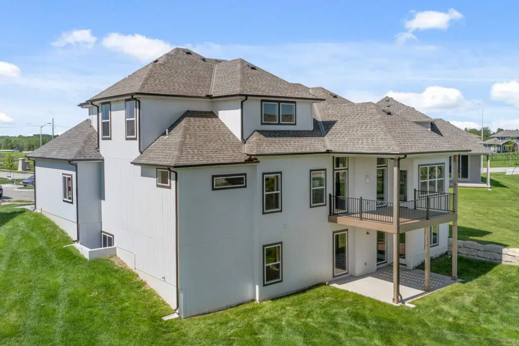 Rear Exterior Of The Comerio Homes Siena 1.5 Featuring A Covered Patio, Elevated Deck, And Walkout Lower Level.