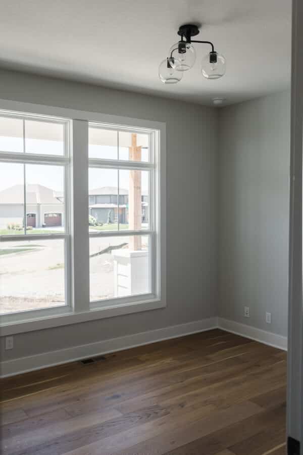 A view of the community from inside the Siena floor plan by Comerio Homes in Coventry Valley of Overland Park, featuring modern wall finish and chestnut flooring.