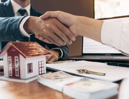 Handshake Over Home Purchase Agreement With House Model And Keys