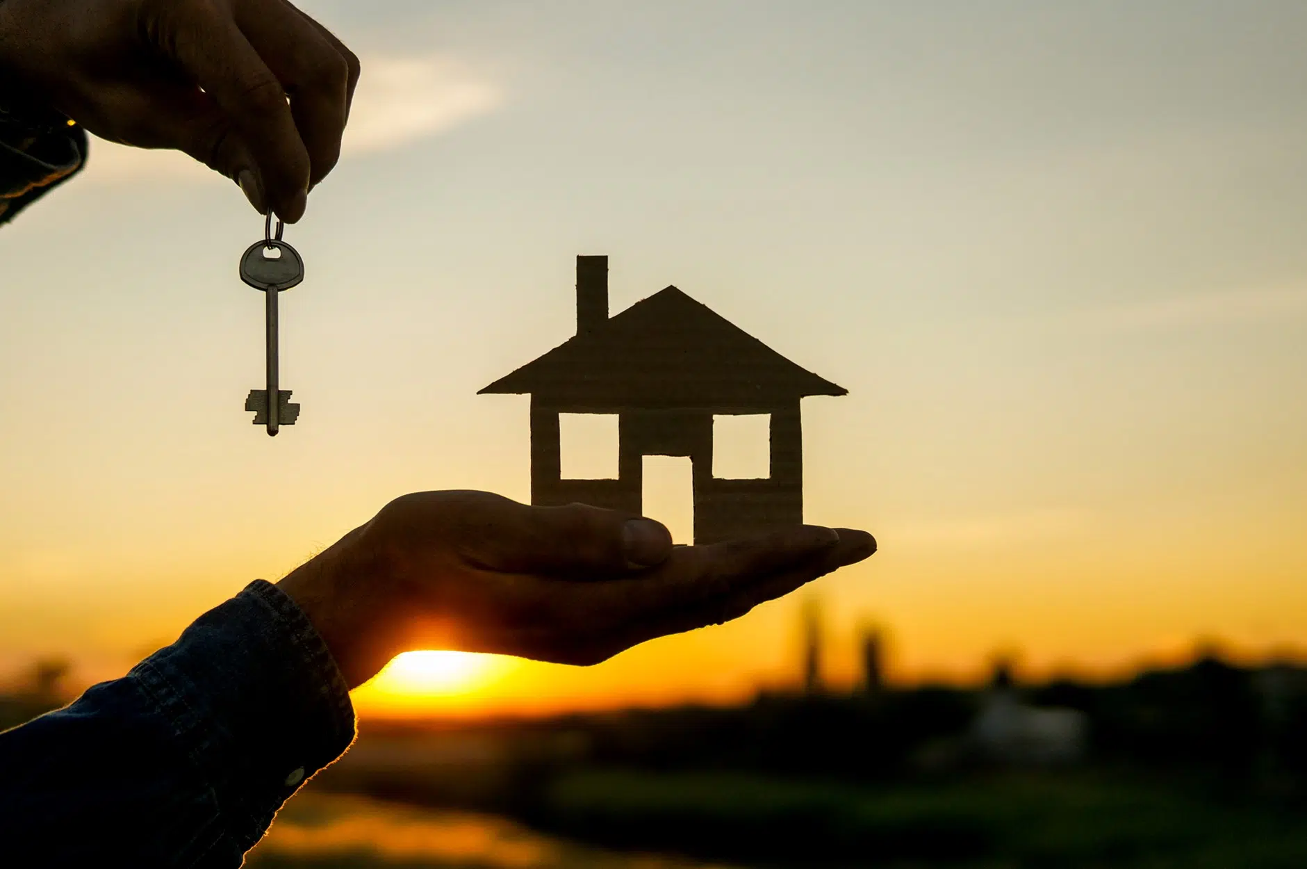 Homeownership concept with house and key at sunset