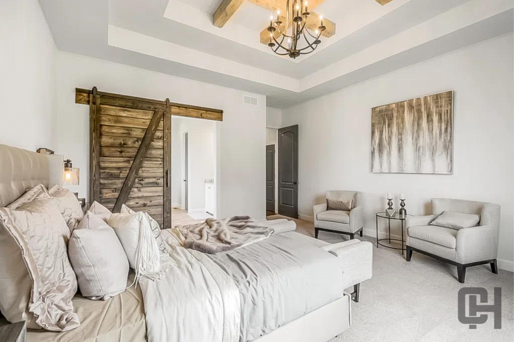 Lago Primary Bedroom With Tray Ceiling, Wood Beams, And Rustic Barn Door
