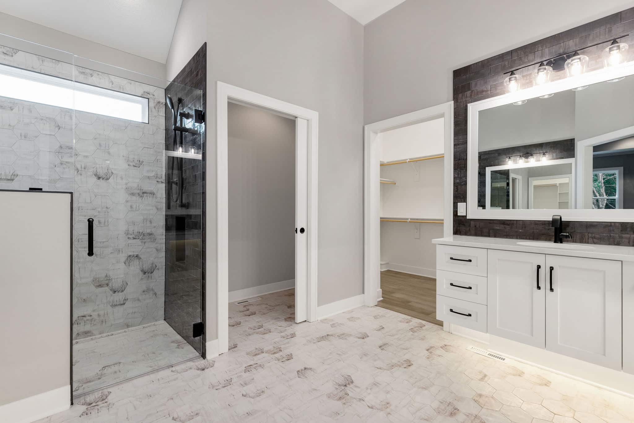 Madalena Zero Entry Shower With Frameless Glass, Contrasting Tile Walls, Black Fixtures, And Seamless Tiled Bathroom Floor.