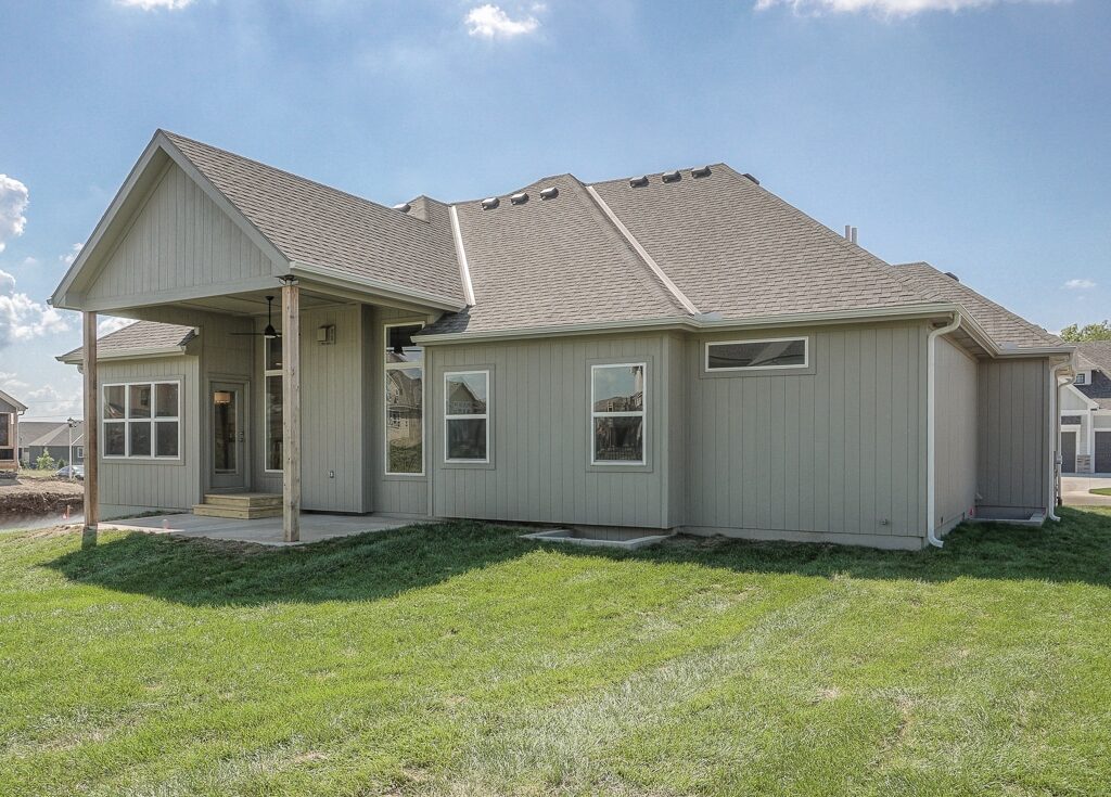 Rear Exterior Of The Siena By Comerio Homes With Covered Patio, Gray Siding And Landscaped Backyard