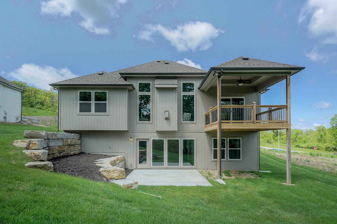Madalena Rear Exterior With A Walkout Basement, Patio, Retaining Walls, And Covered Upper Deck.