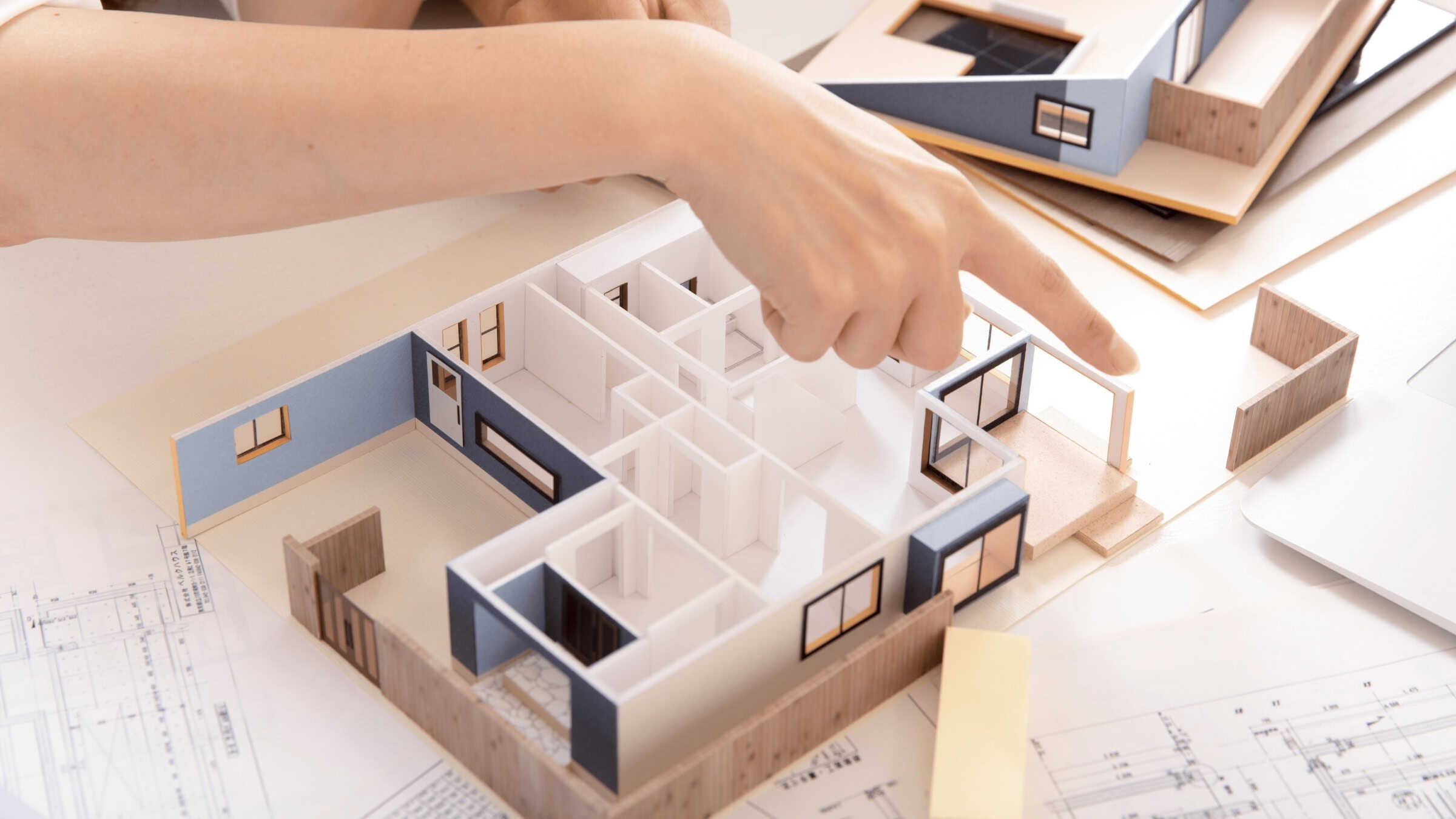 Hands Working On A Home Floor Plan Model Representing Custom Home Design And Planning