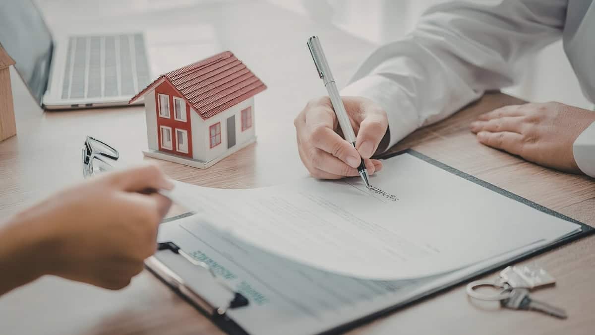 Homeowner Signing Home Building Contract And Agreement Documents With Model House By Comerio Homes