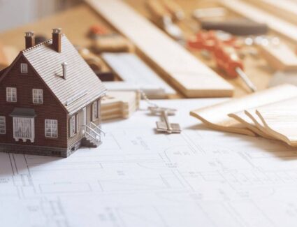 Model House On Architectural Plans With Building Tools And Keys Representing Home Design And Construction