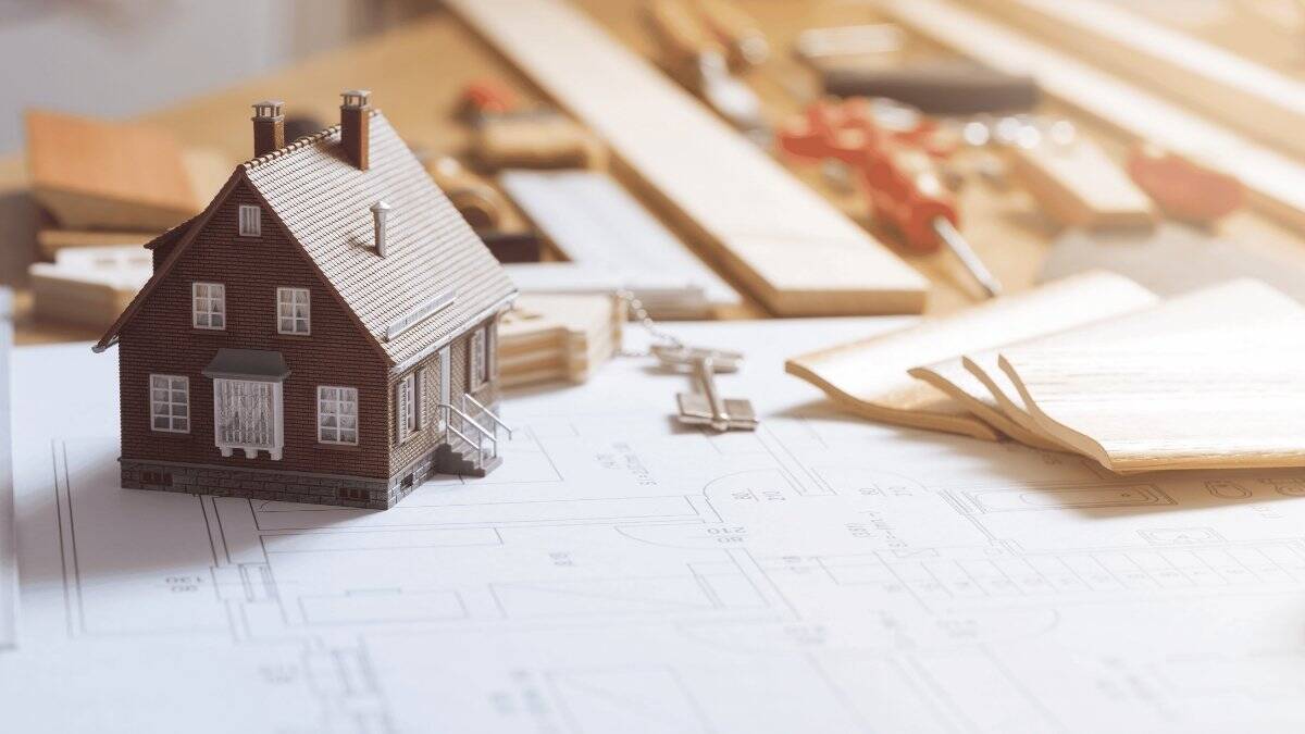 Model House On Architectural Plans With Building Tools And Keys Representing Home Design And Construction