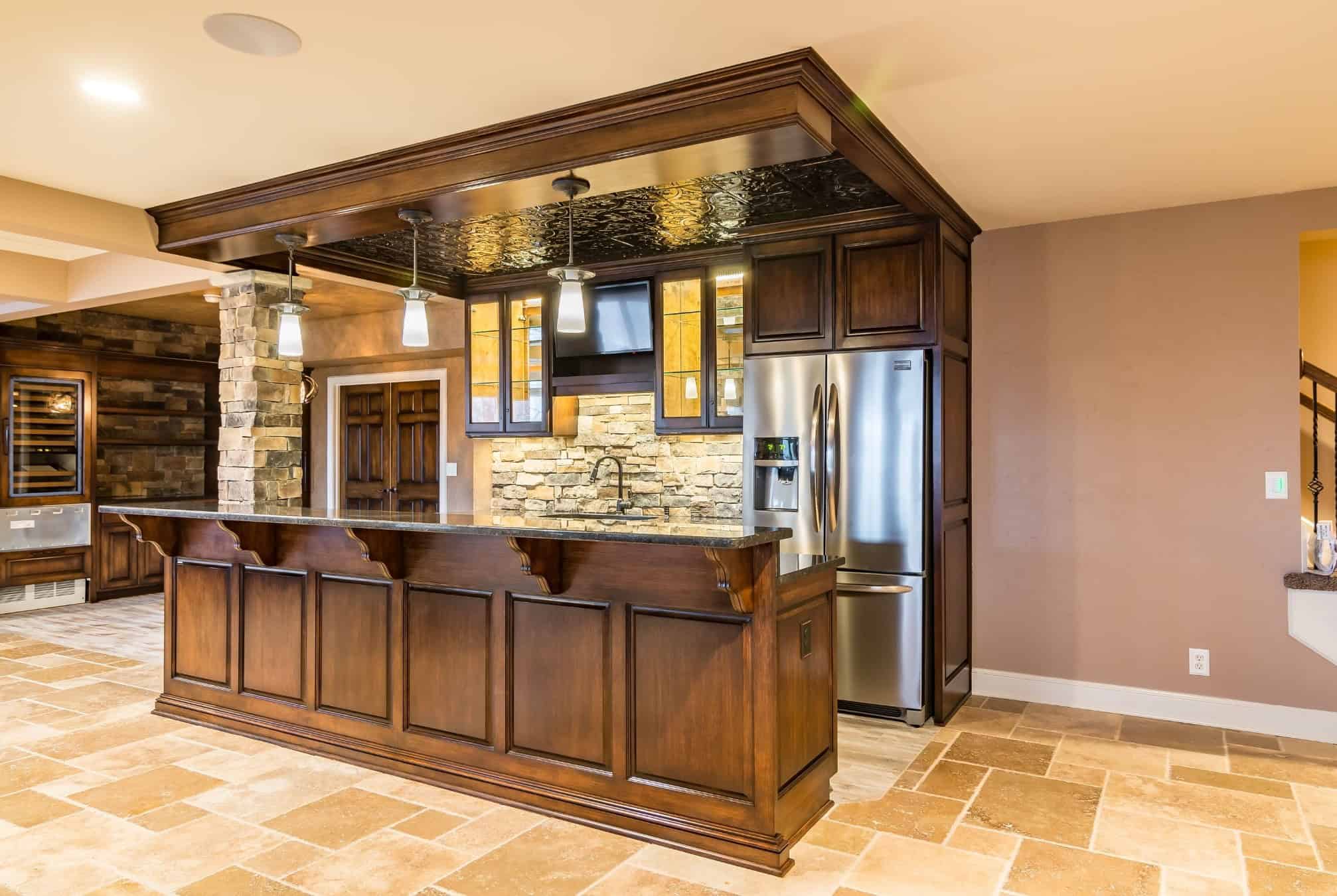 Custom galley bar with wood cabinetry, stone backsplash, and built-in storage by Comerio Homes